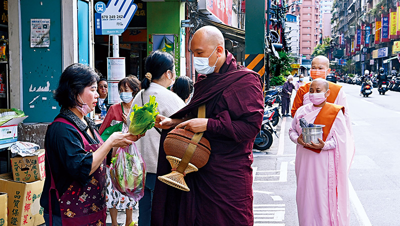 居民奉獻食物，給在華新街托缽的僧侶