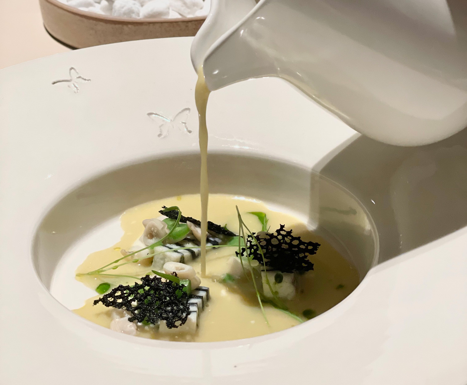 可一湯兩吃的料理，上桌前將高湯倒入盛裝干貝慕斯、竹蟶、四季豆及接骨木花的碗裡。（圖片來源：Papillon提供）