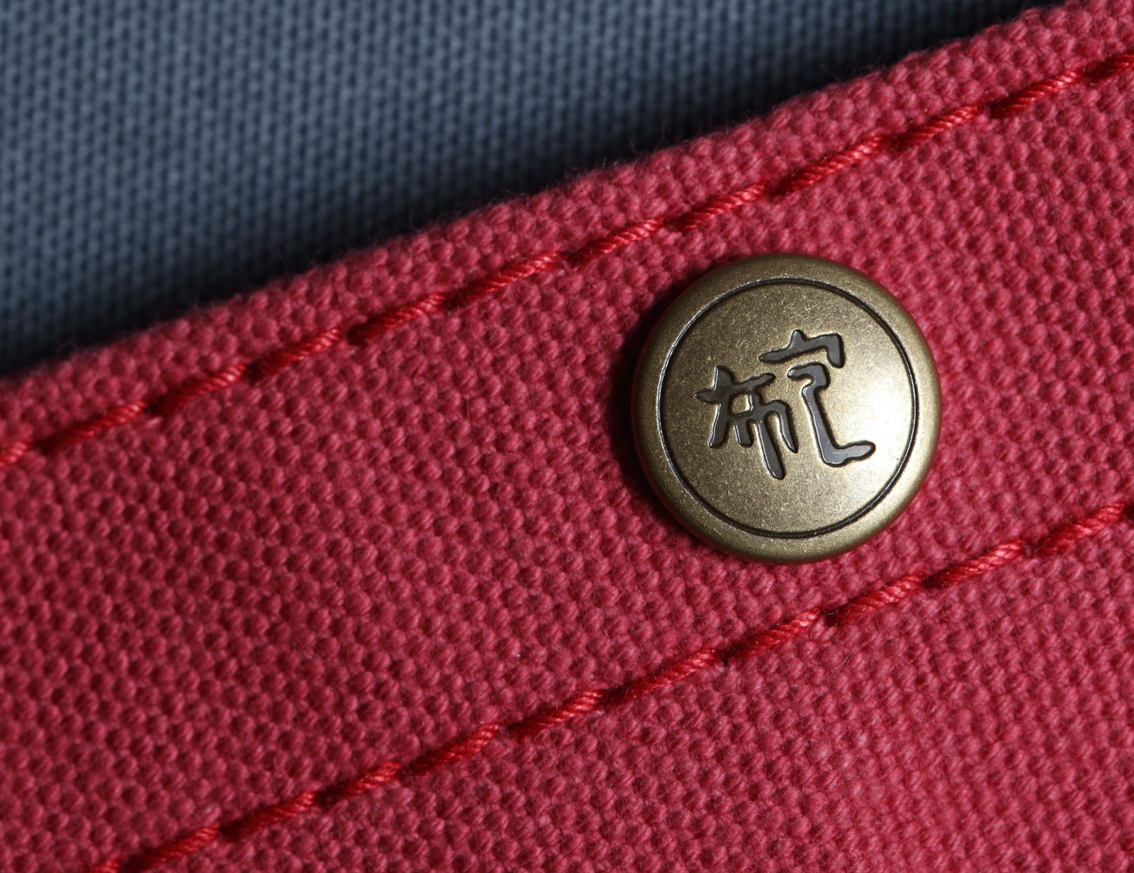 「布包」是信三郎絞盡腦汁自創的一個漢字，帆布包上的鈕扣皆刻印上此字。（攝影／陳炳勳）