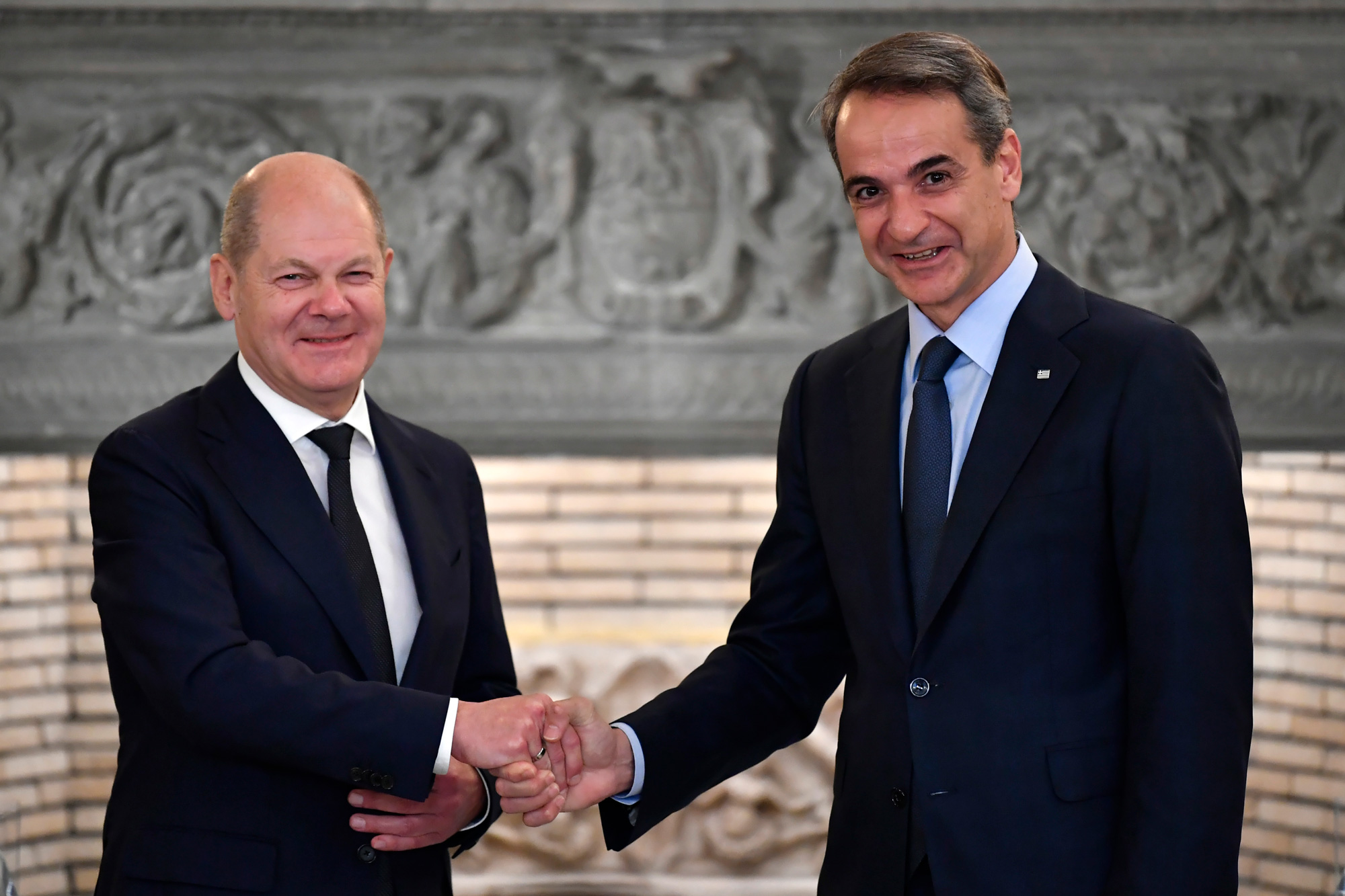 德國總理蕭茲(Olaf Scholz)訪問雅典時,與希臘總理米佐塔基斯(Kyriakos Mitsotakis)握手時,僅獻出手指前半段,即俗稱的魚尾手。(圖片來源/達志影像)