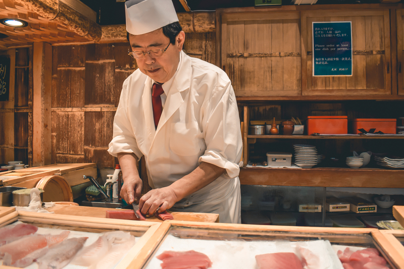 壽司師傅正在板前準備製作壽司的魚料。（圖片來源／dreamstime）