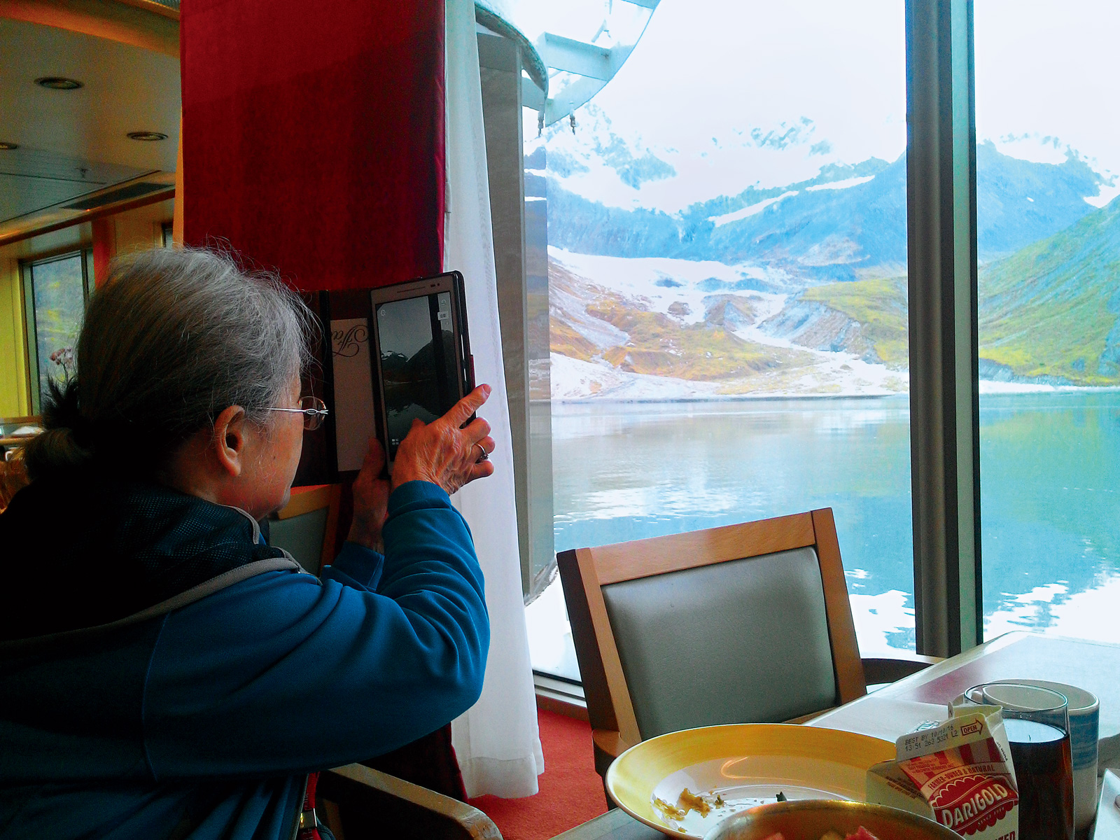 郵輪行經阿拉斯加冰河灣國家公園，媽媽吳素珠興奮拿出手機拍攝美景。陳美筑連忙幫媽媽上傳臉書打卡，紀念此刻。（圖片來源／陳美筑）