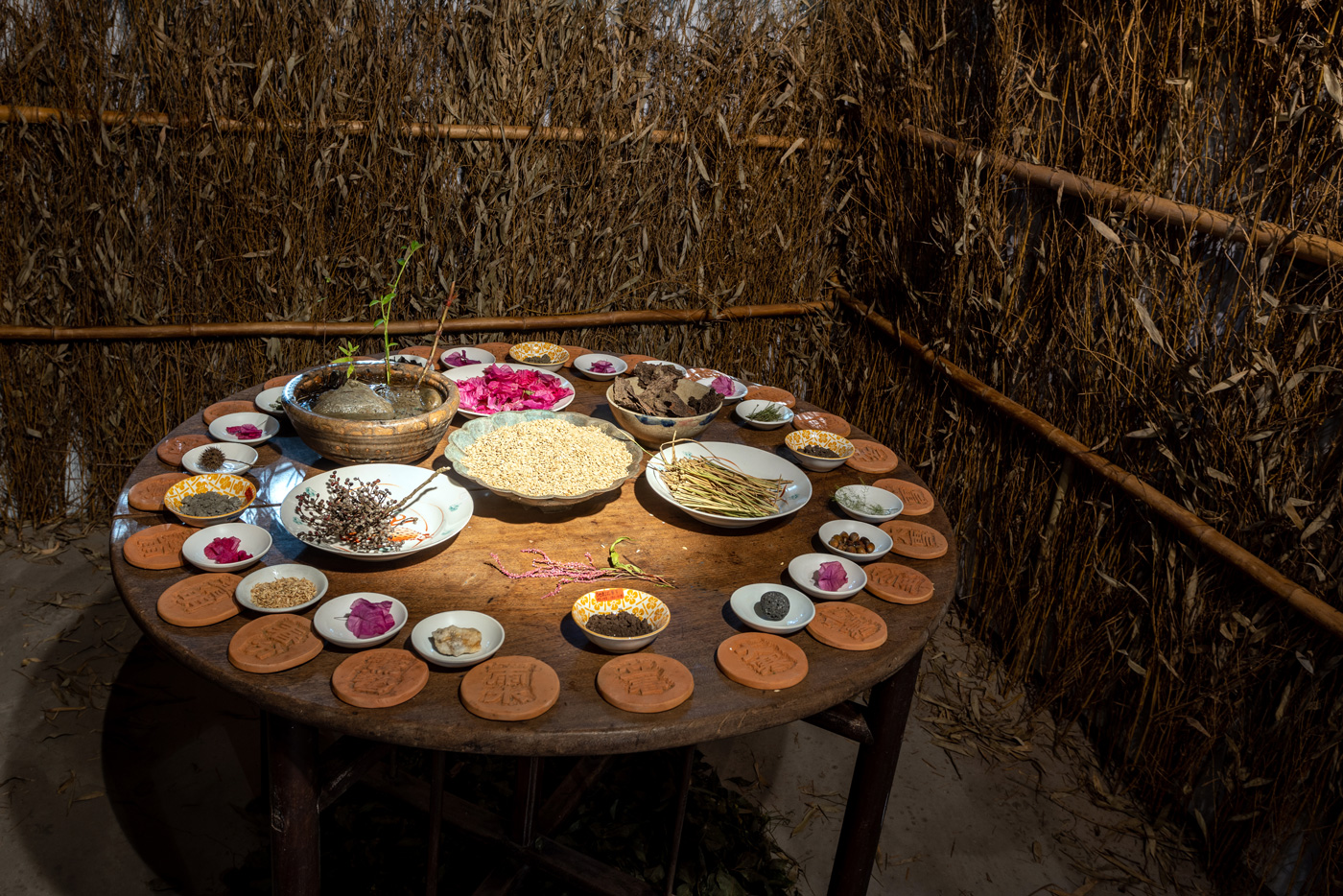 木質圓桌來自池上鄉親的老家，土壤則來自池上四方，桌上器皿中盛裝了在地的泥土、稻米、稻桿、灰燼、水、雜蕪、草籽與野蔬。這是展覽作品《池上的味道》。（圖片來源／台灣好基金會）