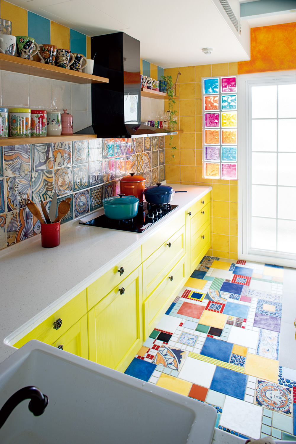 檸檬黃廚具與大地黃壁面，壓住各式圖案花俏的花磚。（圖片來源／集集設計）