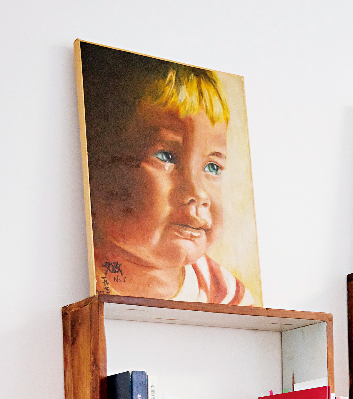 21歲時，林文政翻閱書本自學油畫，看著書籤畫下一位流淚男孩，人生第一張作品仍保留至今。（攝影／羅芸）
