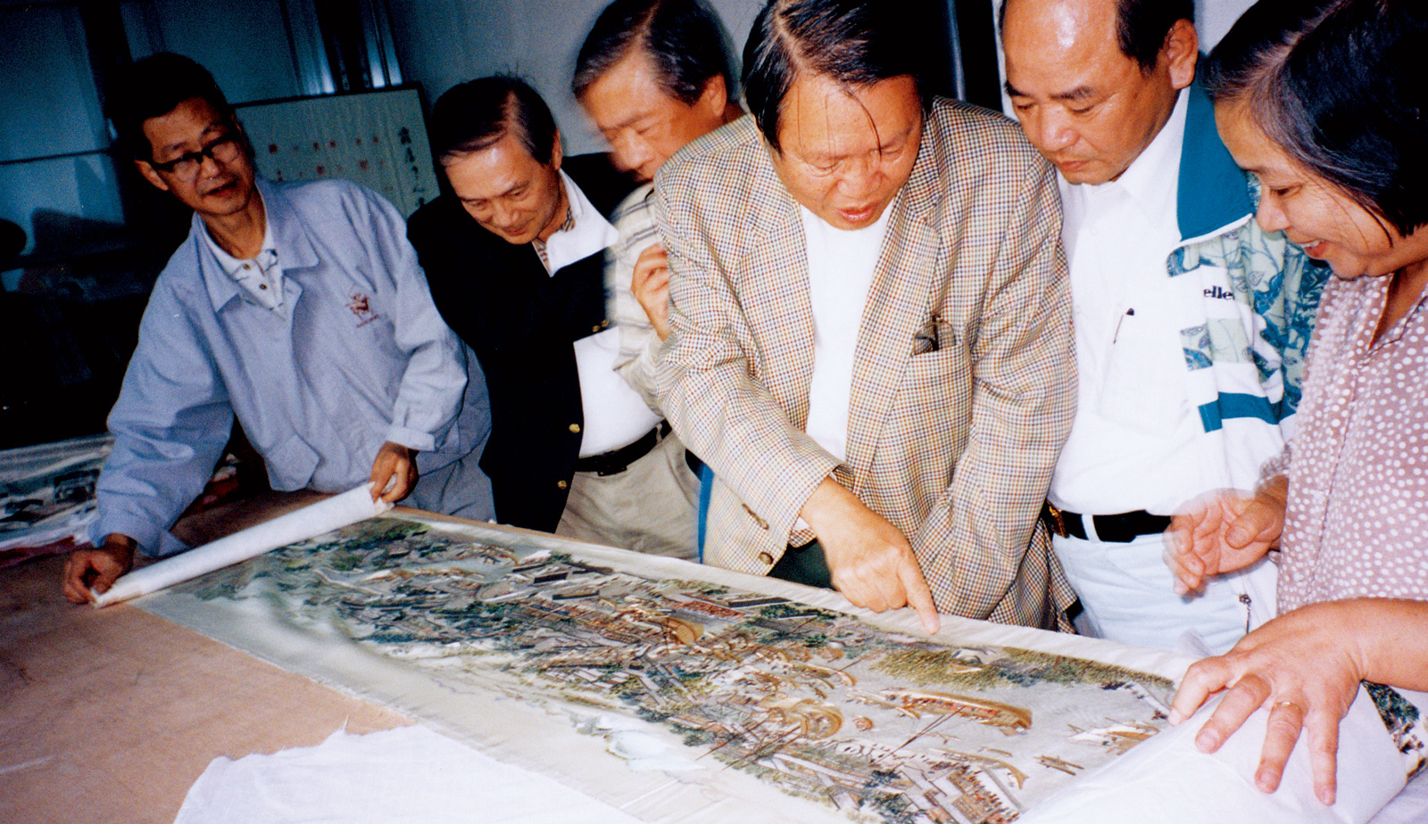 邱再興1991年於蘇州蘇繡博物館，檢視繡畫名作《姑蘇繁華園》，並由蘇繡國寶級大師顧文霞（右一）親自解說。（圖片來源／鳳甲美術館）
