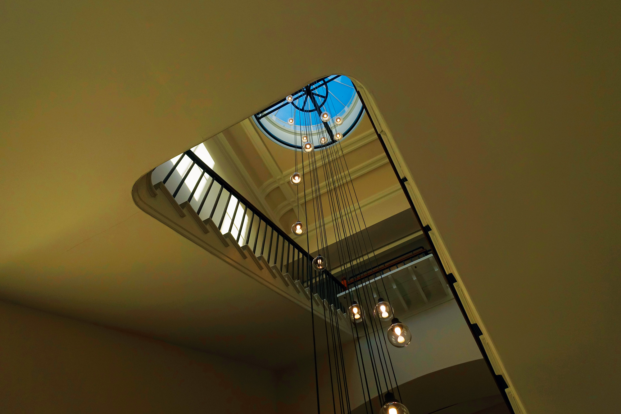大廳擁有過去歷史建築的莊嚴感，從玻璃圓形屋頂垂吊而下的燈則增添現代感。（圖片來源／張智強）