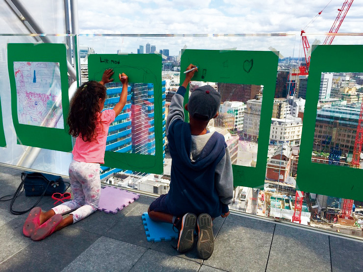 小朋友在聖瑪莉艾克斯30號大樓的玻璃窗上，描繪城市高樓。（圖片來源／Archikids）