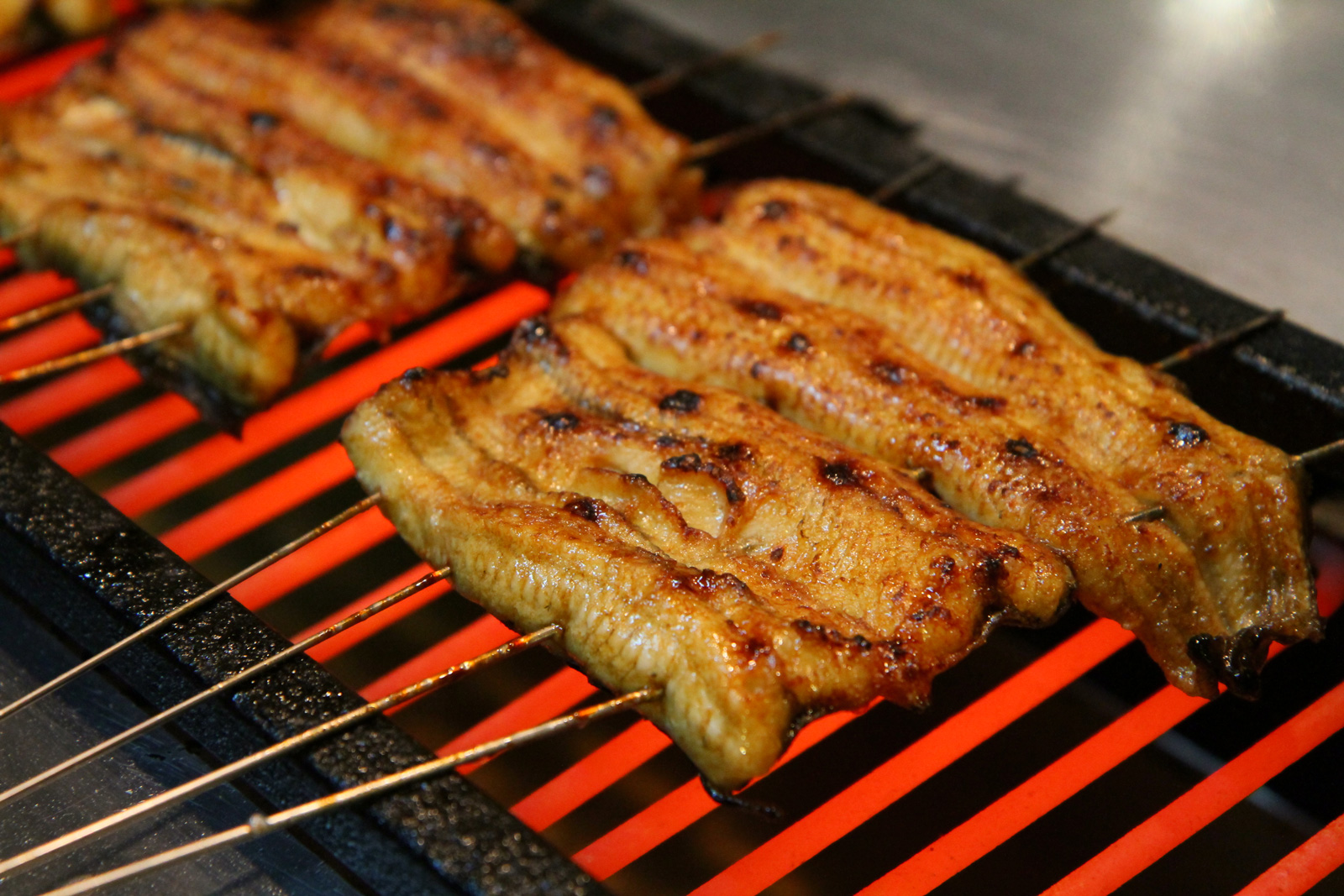 濱松屋將鰻魚串上鐵條烤3分鐘左右，放到木箱蒸籠裡蒸軟再到烤爐上烤，是關東做法。（攝影：呂恩賜）
