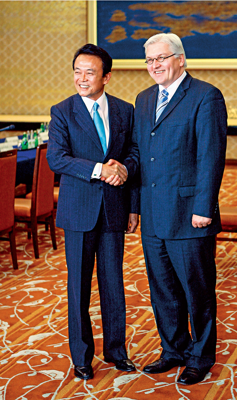 時任德國外交部長史坦麥爾2006年訪問東京，與時任日本外務大臣麻生太郎握手，兩人穿著3顆釦西裝，但繫釦方式不同，也創造出不一樣的視覺感受。（圖片來源：達志影像）