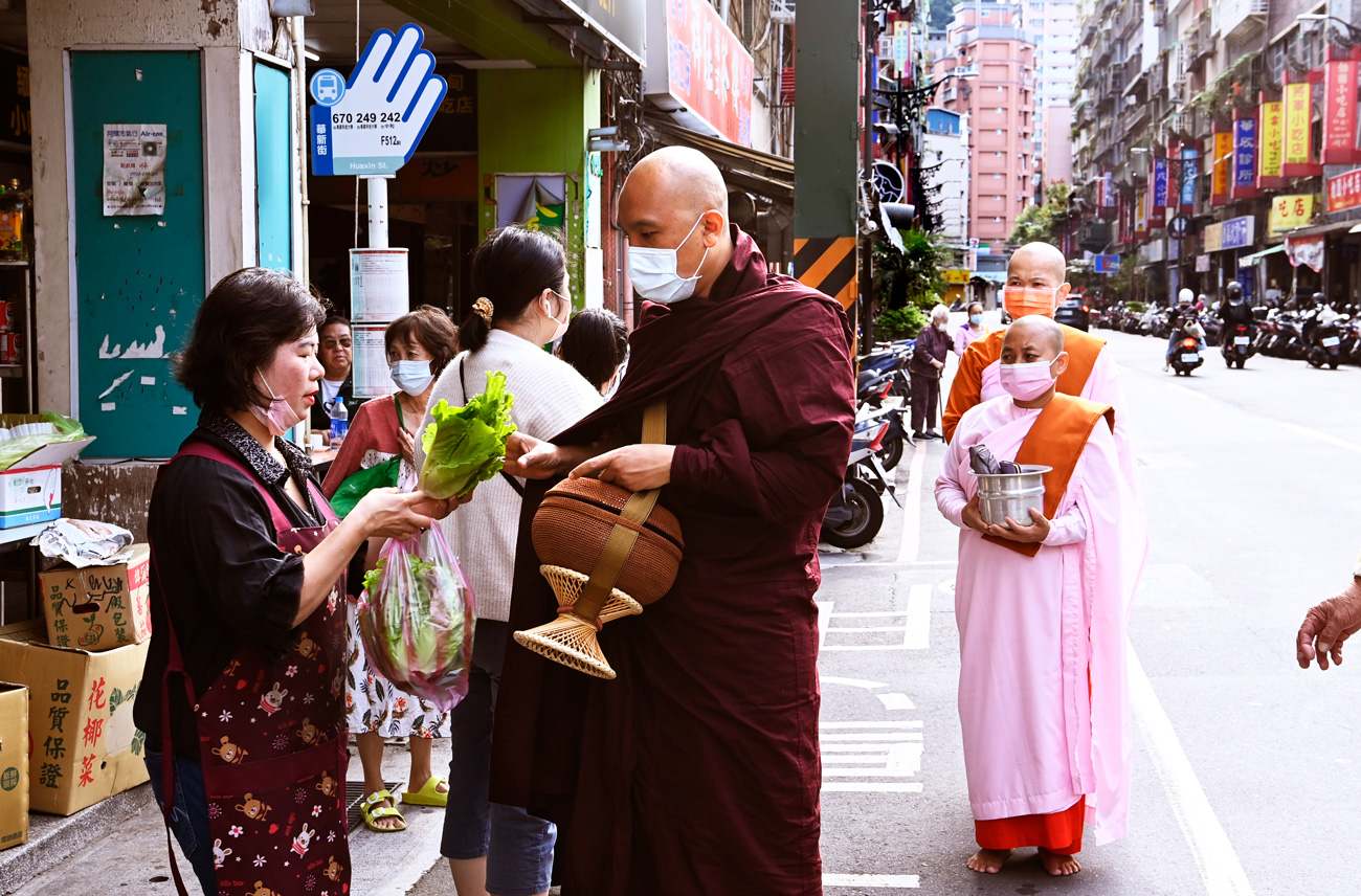 居民奉獻食物，給在華新街托缽的僧侶。（攝影：程思迪）