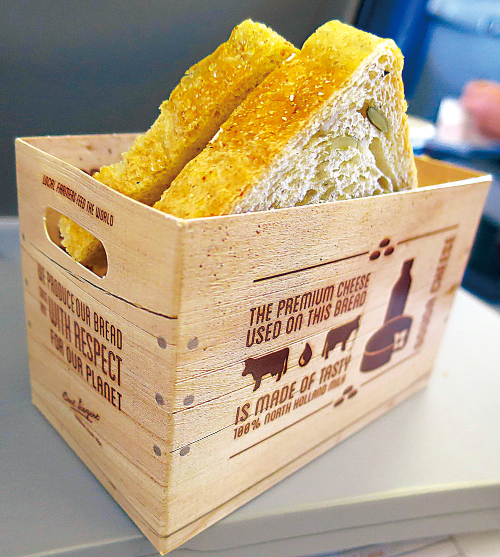 近期印象深刻的食品包裝，則是荷蘭航空的歐洲內陸短程班機上的起司三明治，一反過去常見的平淡無奇塑膠盒、紙盒、塑膠袋或紙袋，宛若農場木箱樣貌的紙製小餐籃，形式簡單但優美的圖案文字寫明用的是荷蘭在地產製的Gouda起司，還短短附上一段這起司的歷史源流特色故事；別致用心，美味與印象都加分。（攝影：葉怡蘭）