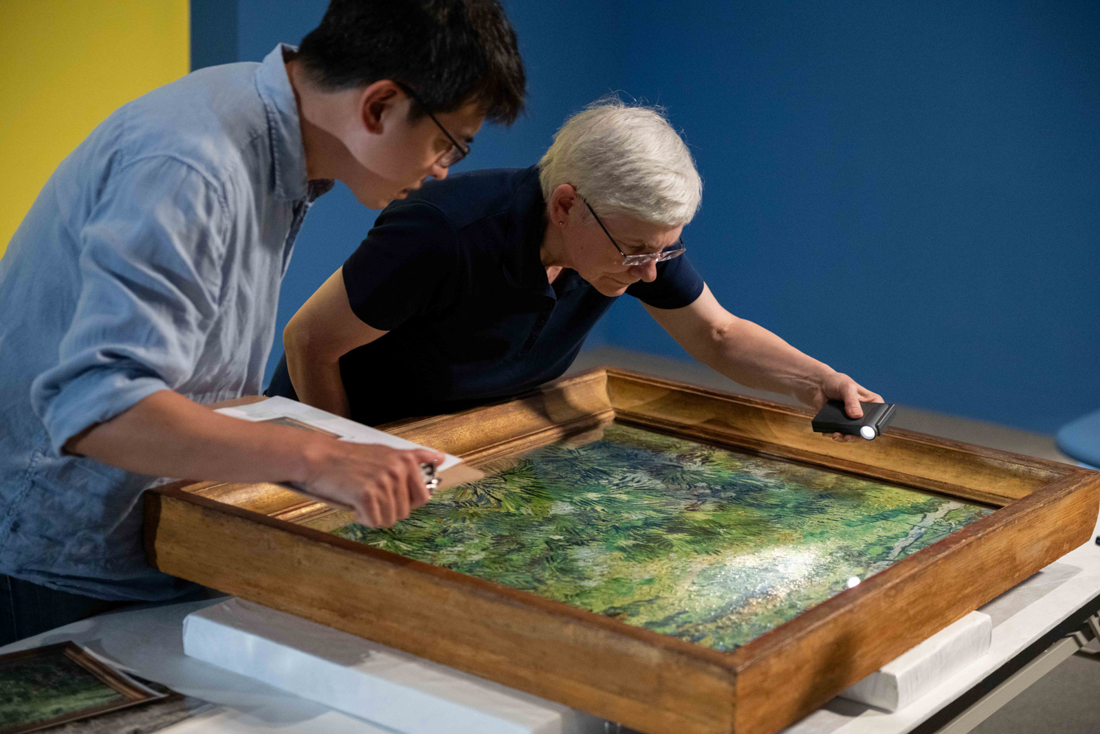奇美博物館《英國國家藝廊珍藏展》布展過程，兩館的修復師仔細檢視梵谷的作品〈長草地與蝴蝶〉。（圖片來源：奇美博物館提供）