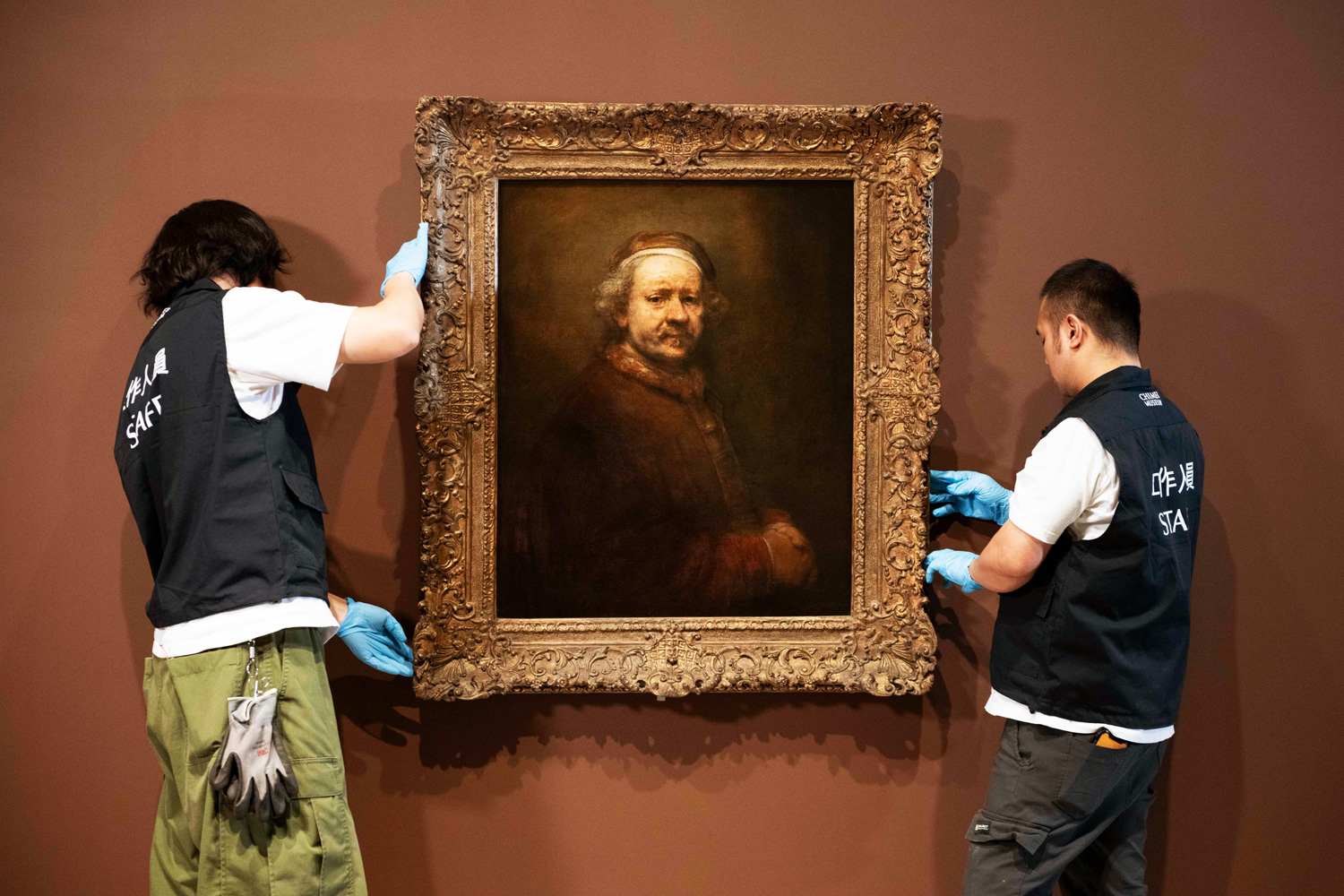 奇美博物館《英國國家藝廊珍藏展》布展過程，工作人員將林布蘭的作品〈六十三歲自畫像〉掛於牆上。（圖片來源：奇美博物館提供）