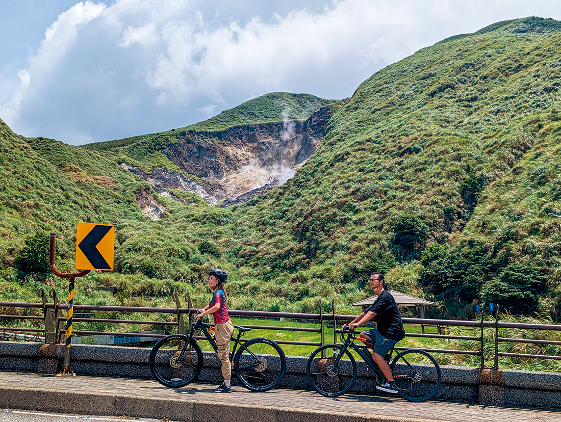 電輔自行車行經小油坑橋，小油坑冒著煙霧，這裡火山噴氣孔全年噴出硫氣與蒸氣。（攝影：柯曉翔）