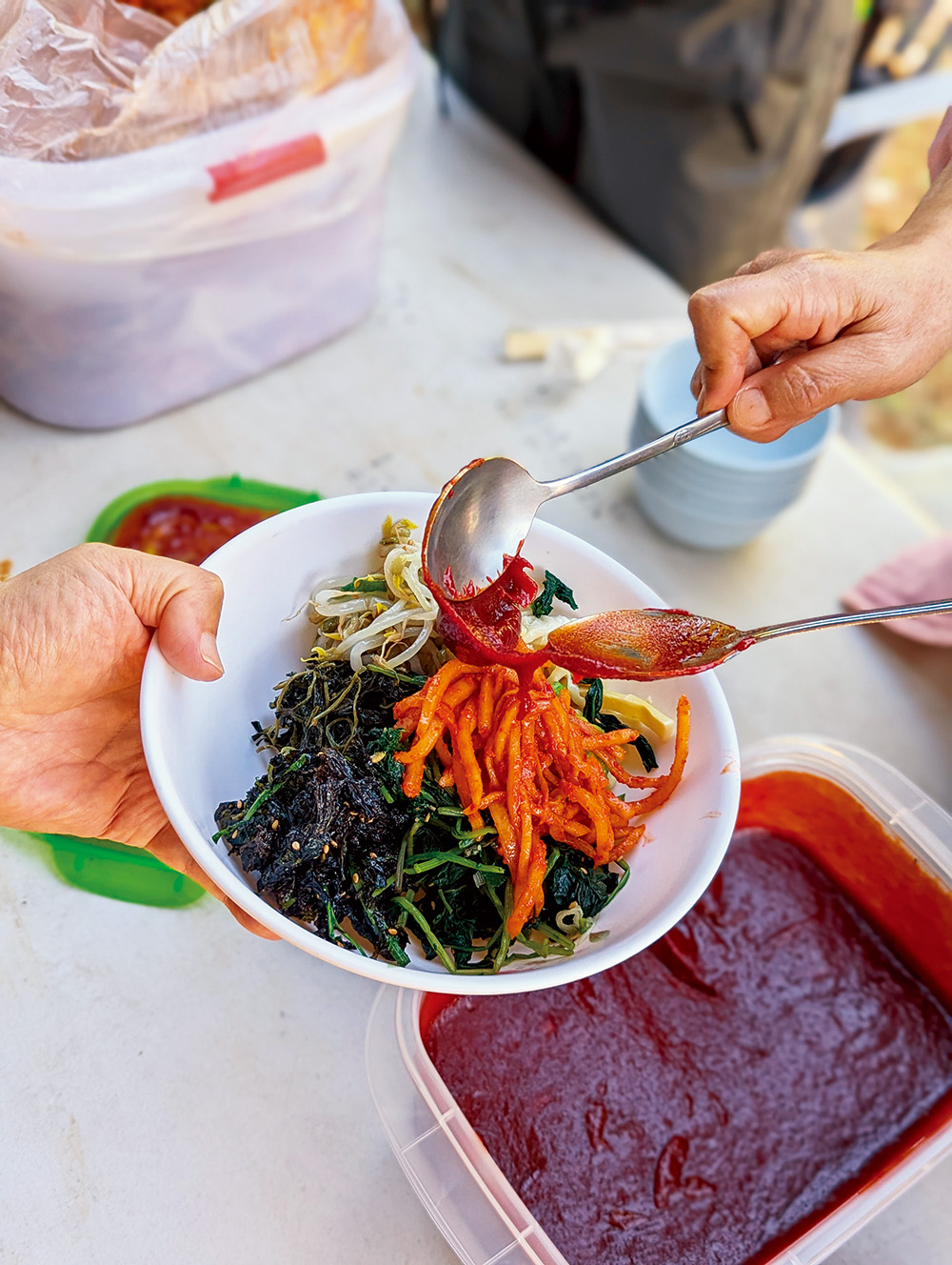 在地村民為旅客的碗裡添上蔬菜、白飯、荷包蛋和辣醬，健行途中吃得到韓國國民美食拌飯。 （攝影：柯曉翔）