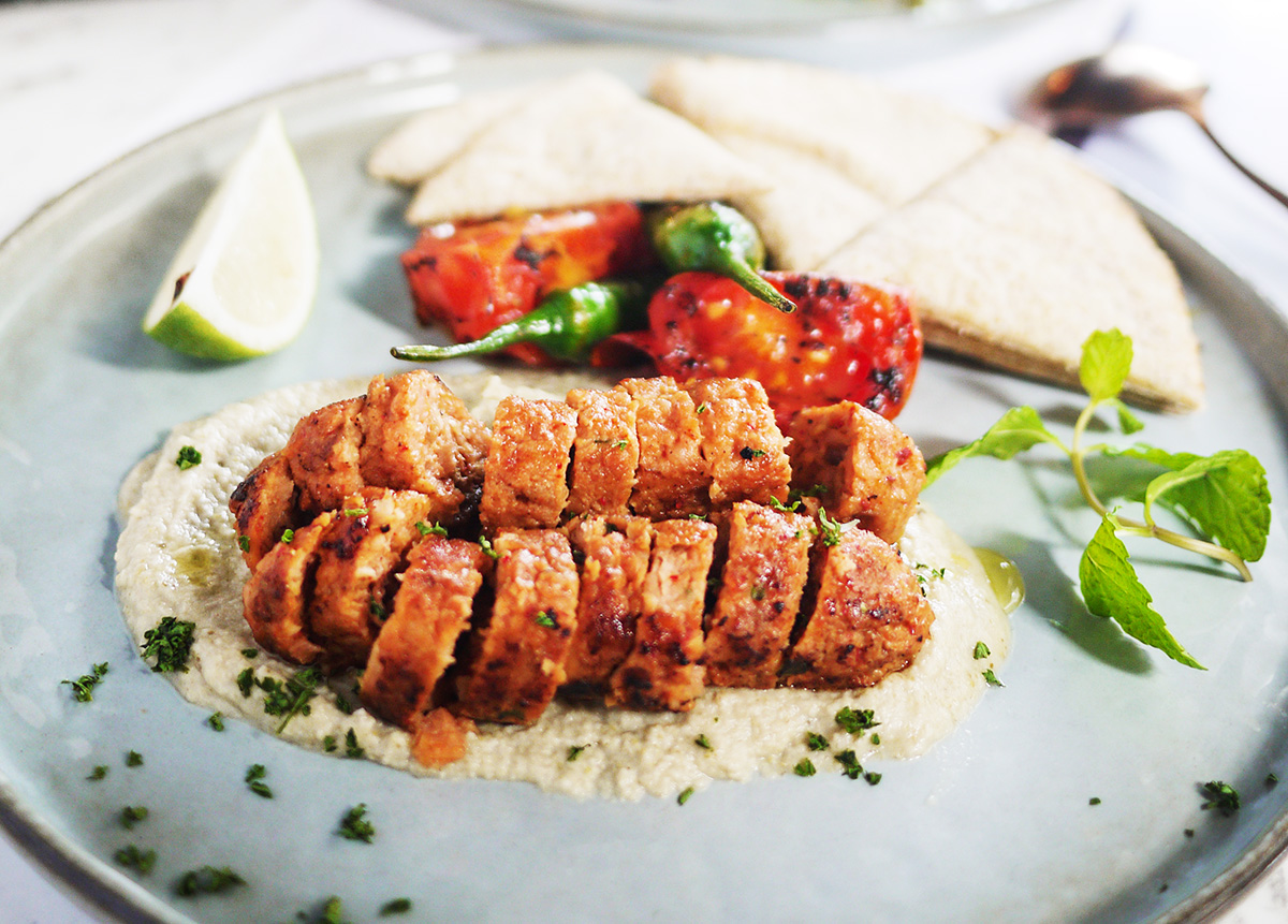 為葷食者設計的蔬食餐廳「Baganhood」以小茴香、孜然等香料醃漬植物肉，煎烤切片後，與口袋餅、茄子泥佐用，即為一道經典中東菜餚。（圖片來源：Baganhood提供）