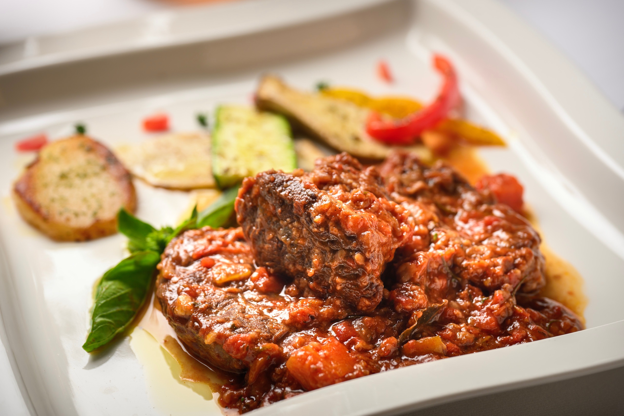 「精選米蘭式精燉牛肉套餐」以米蘭經典配方為底，主廚先將牛腱香煎鎖汁，再加入蕃茄、西洋芹、洋蔥熬成的醬汁，送入烤箱低溫燉煮兩小時，最後配上爐烤時蔬，堆疊出溫潤而濃郁的風味。